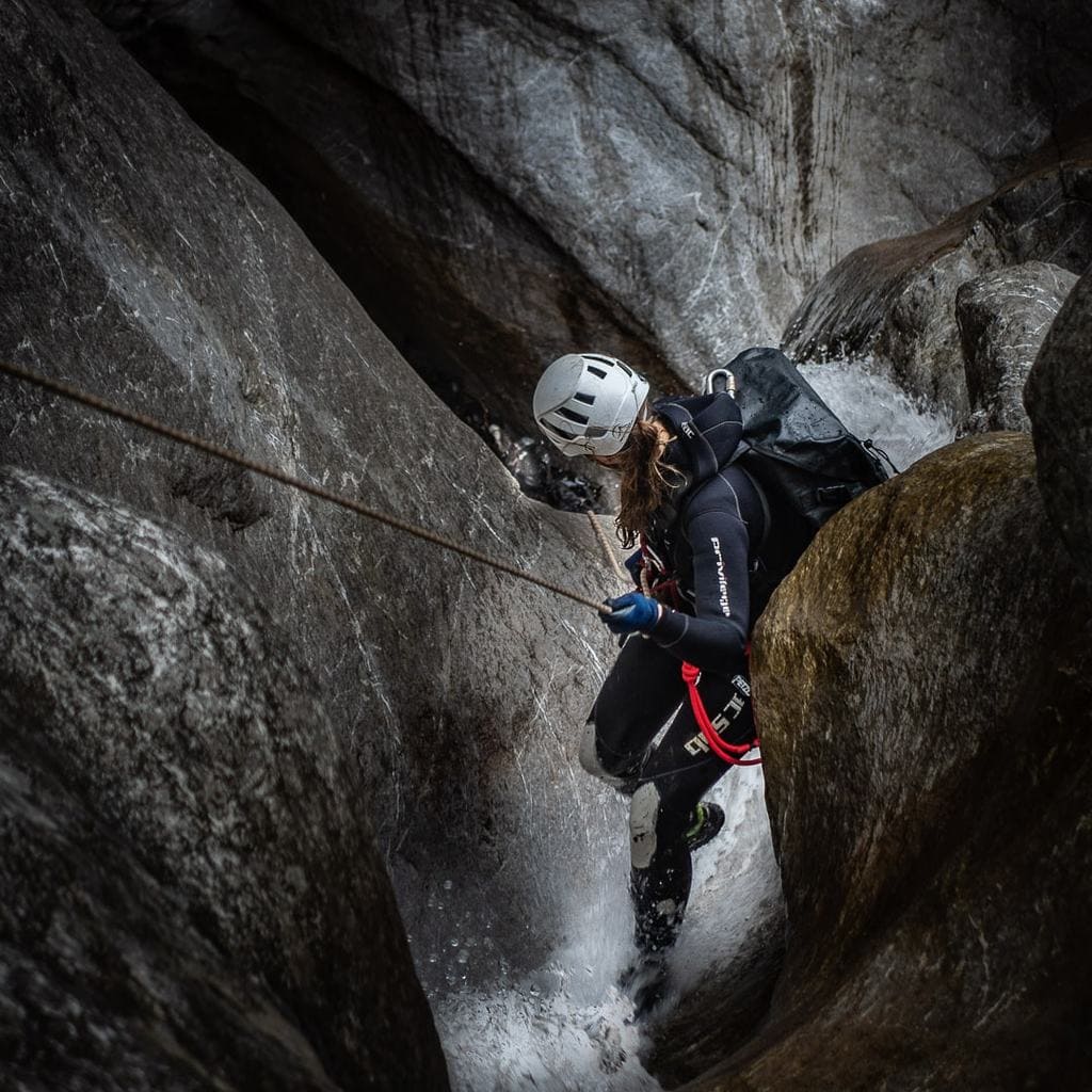 Cave explorer descening with rope with waterproof backpack