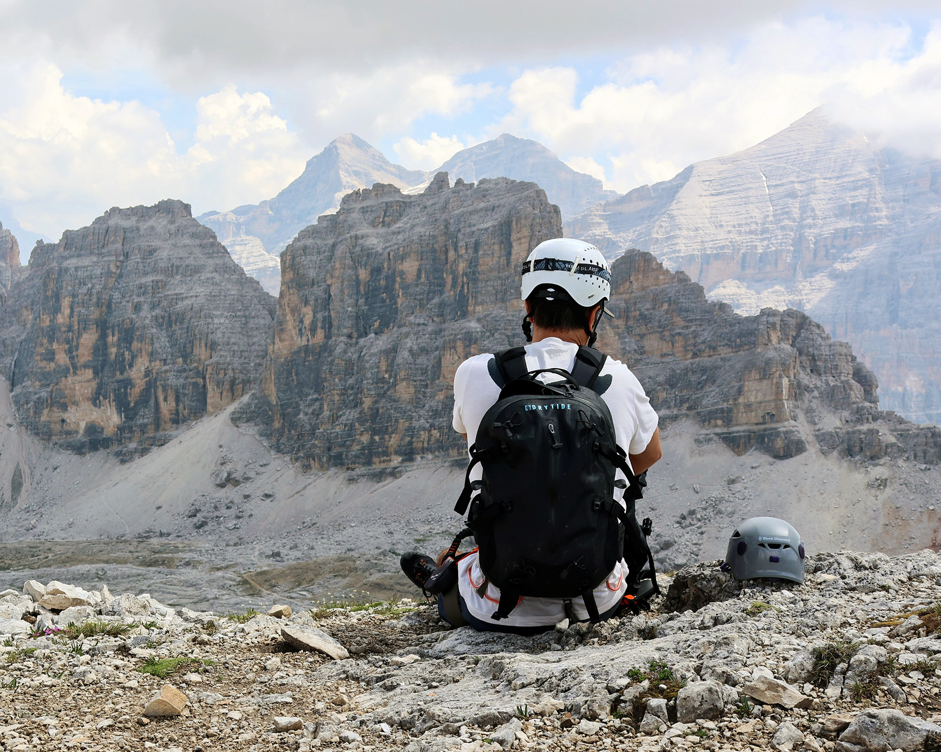 Hiker with DRYTIDE waterproof backpack in rugged mountain terrain.